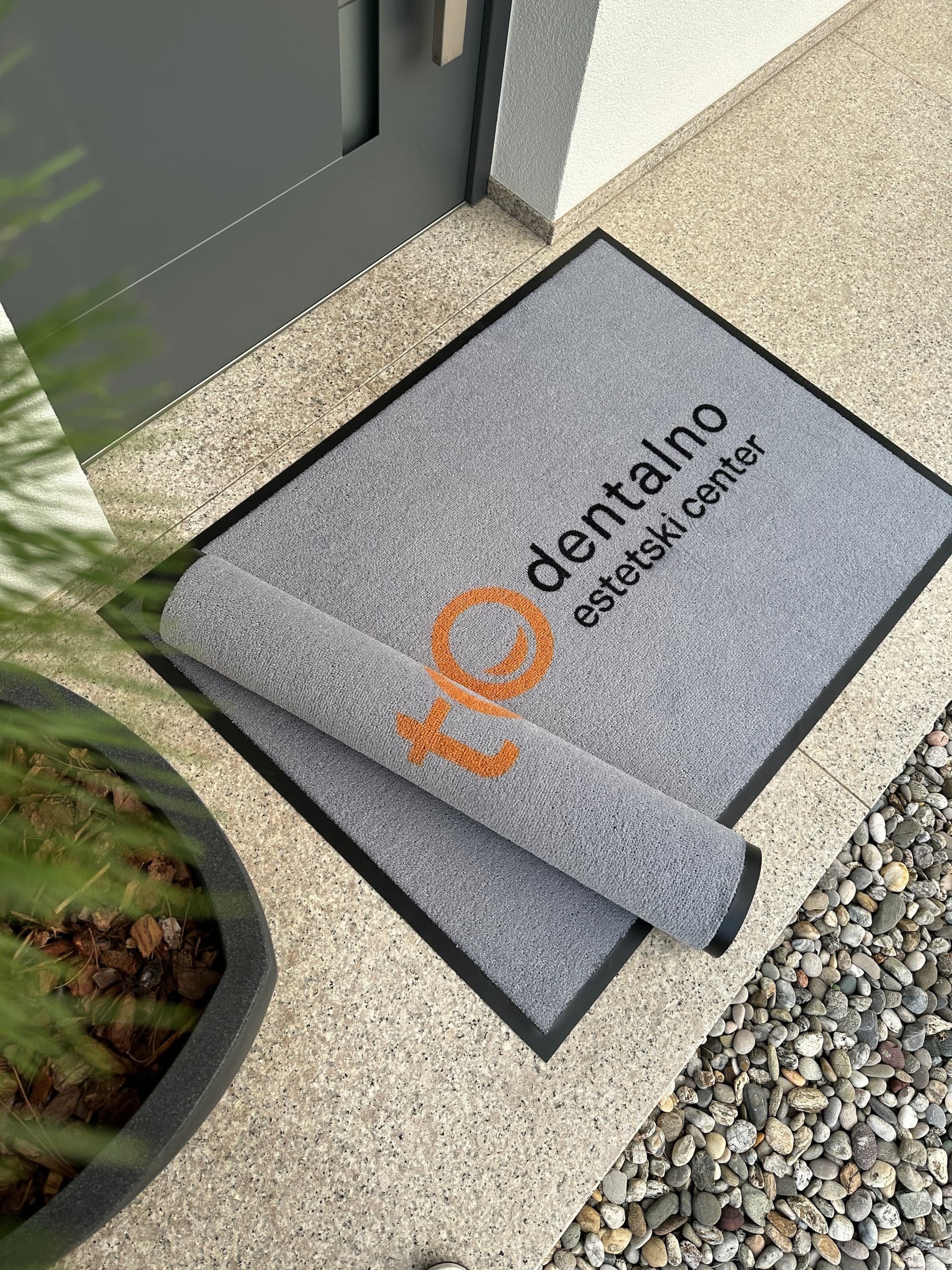 Hotelski ulaz s elegantnim logo otiračem.