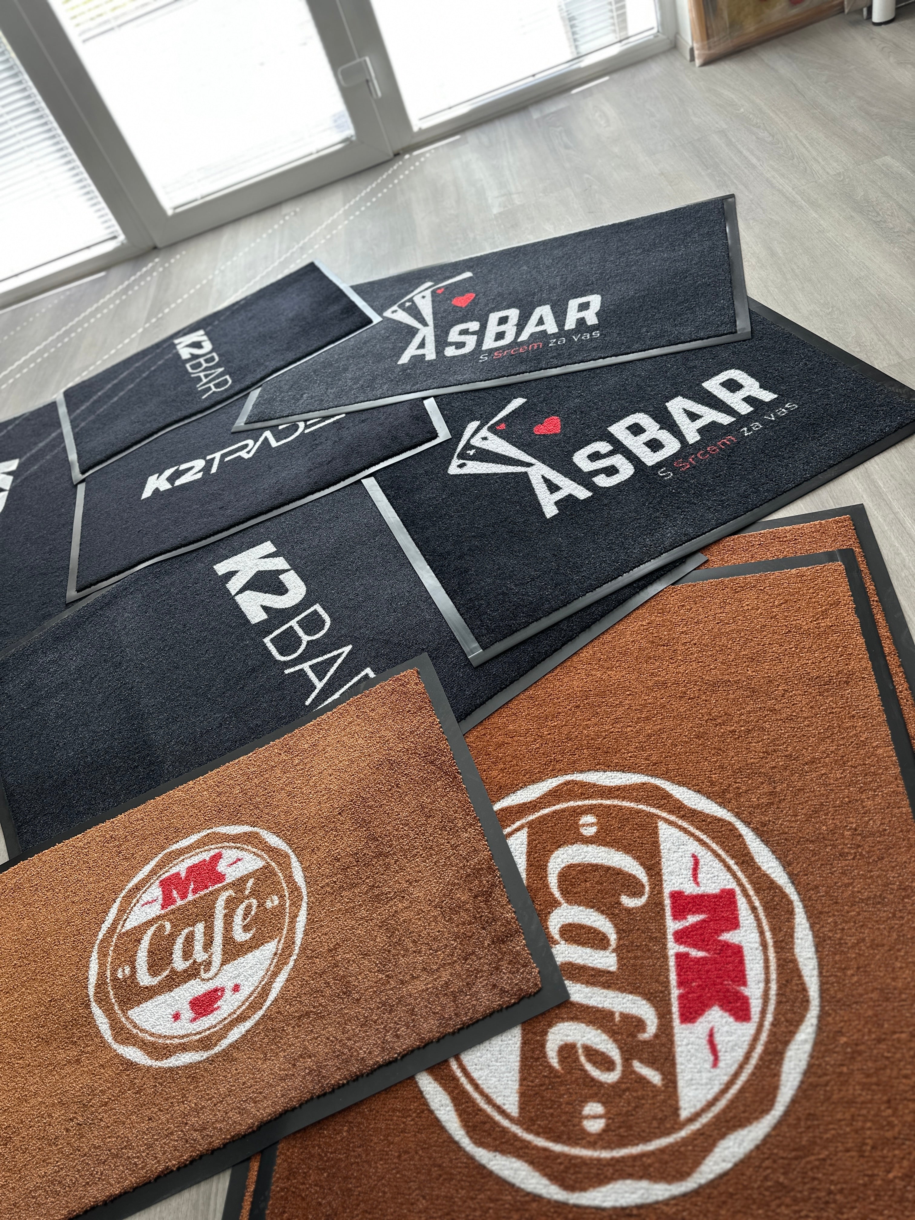 Trije predpražniki v različnih barvah z logotipi