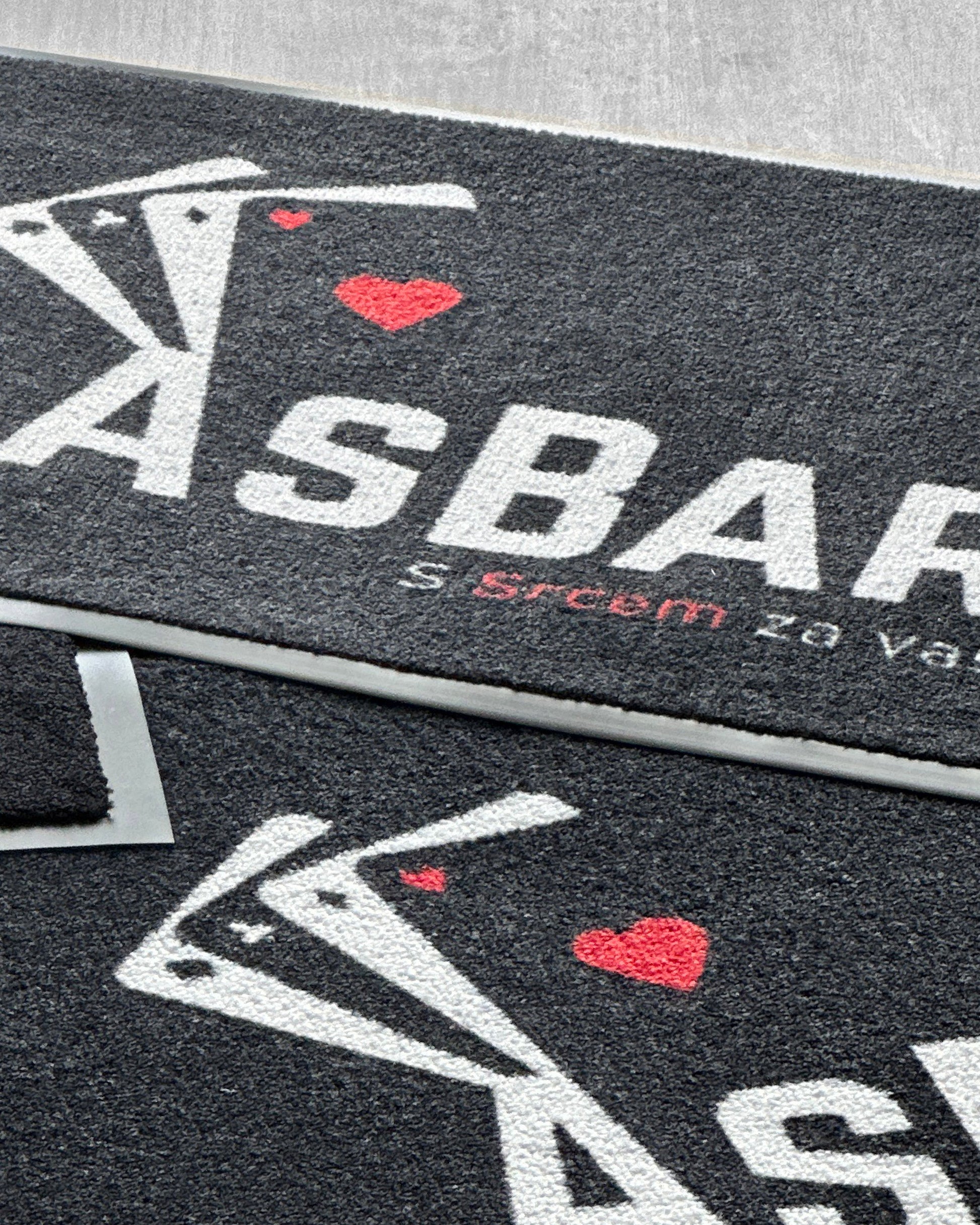 Predpražnik z logotipom pred vhodom v podjetje